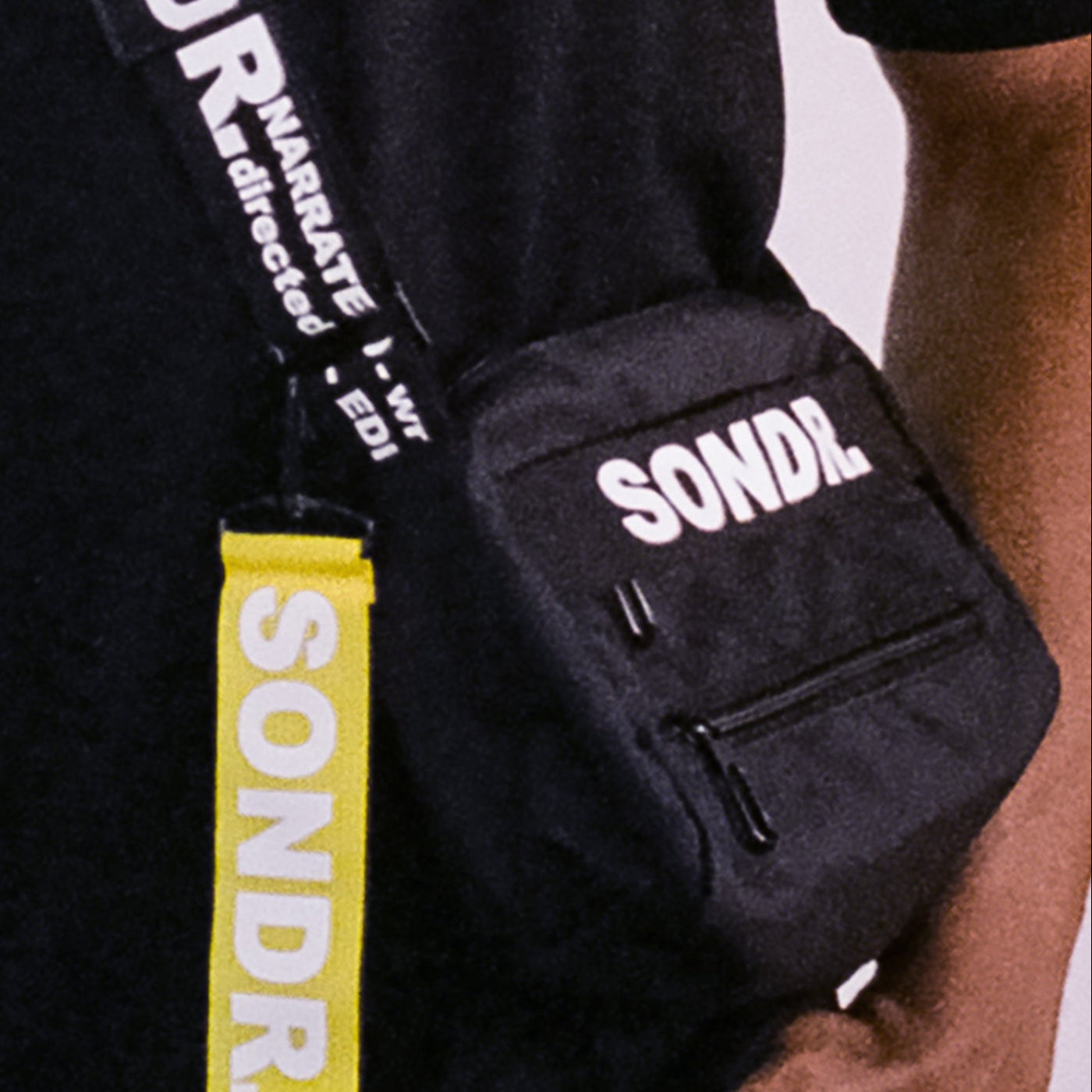 Close up shot of SONDR. Black Side Bag Product Image. Showing shoulder trap print & yellow tag